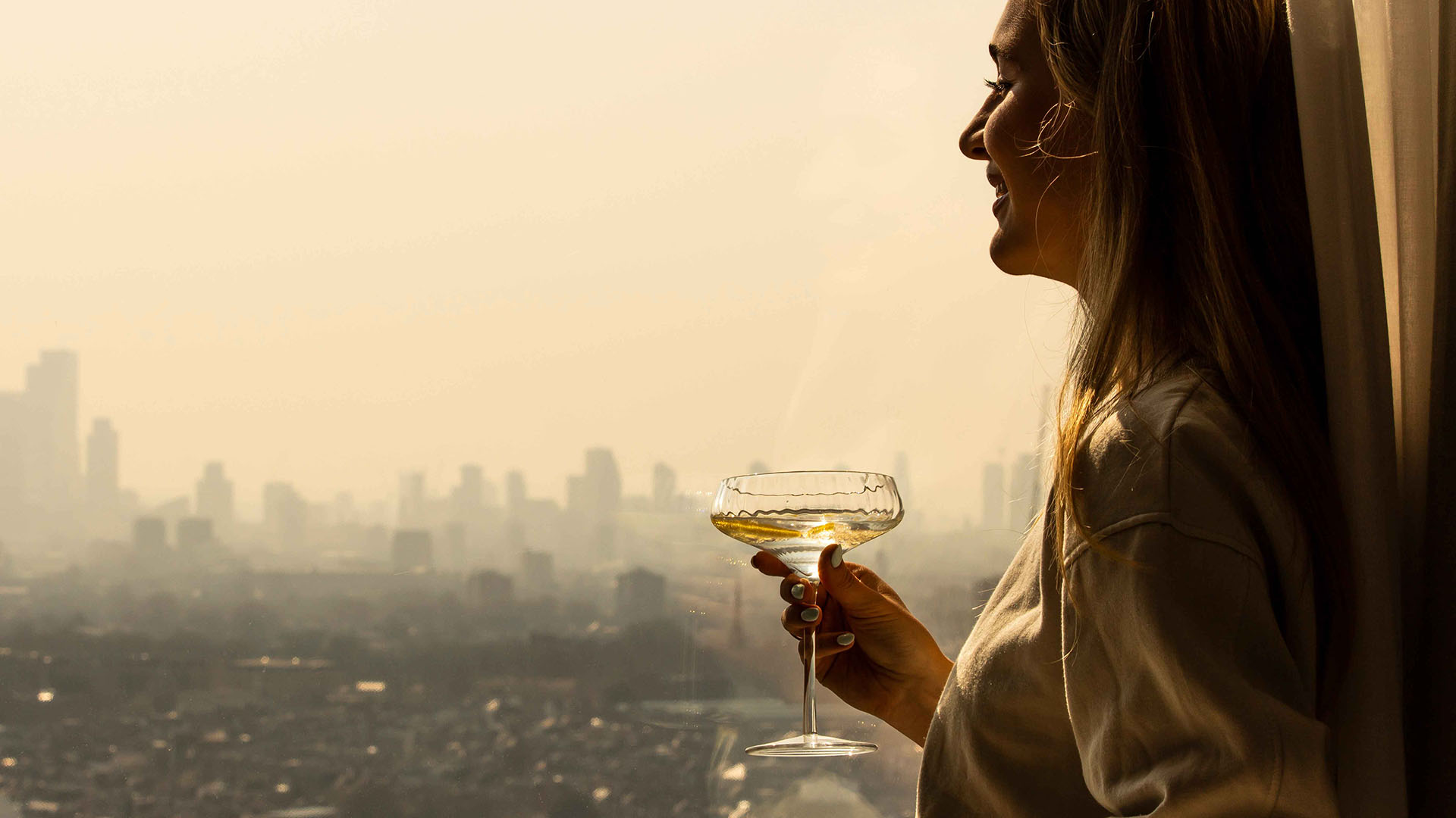 Female looking outside window with glass of wine