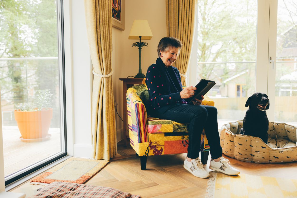 Woman sat looking at Tablet next to black dog